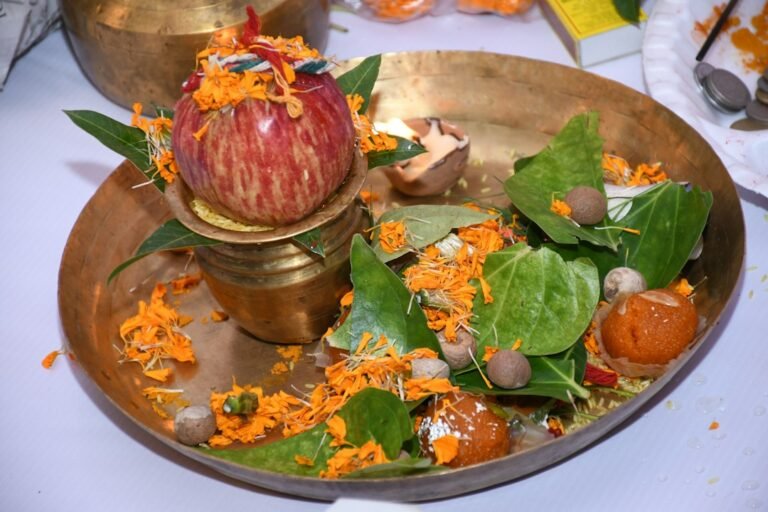 Brass plate with betel leaves, flowers, fruit and a lamp